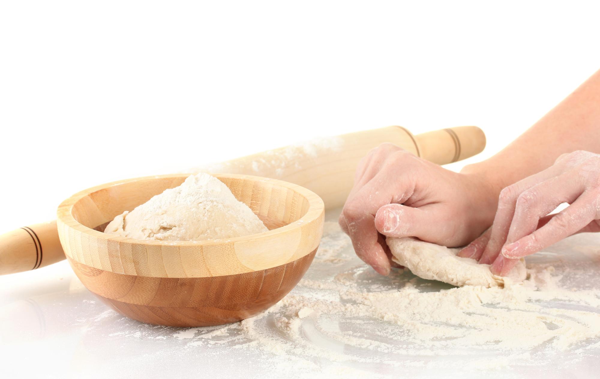Dettaglio mani che lavorano impasto su tavola